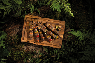 a Tram wooden cutting board with beef skewers on it