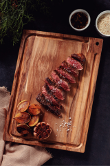 a tram wooden cutting board with steak slices and spices on the board