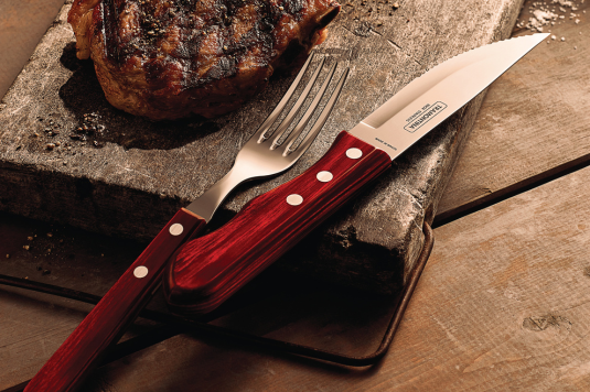 This is an image of a steak knife and fork and both of them have a very beautiful dark red wooden handle and a steak on the left of the knife and fork